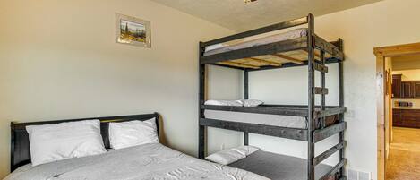A bunk bed room with a ceiling fan, a single bed, and a small picture on the wall.