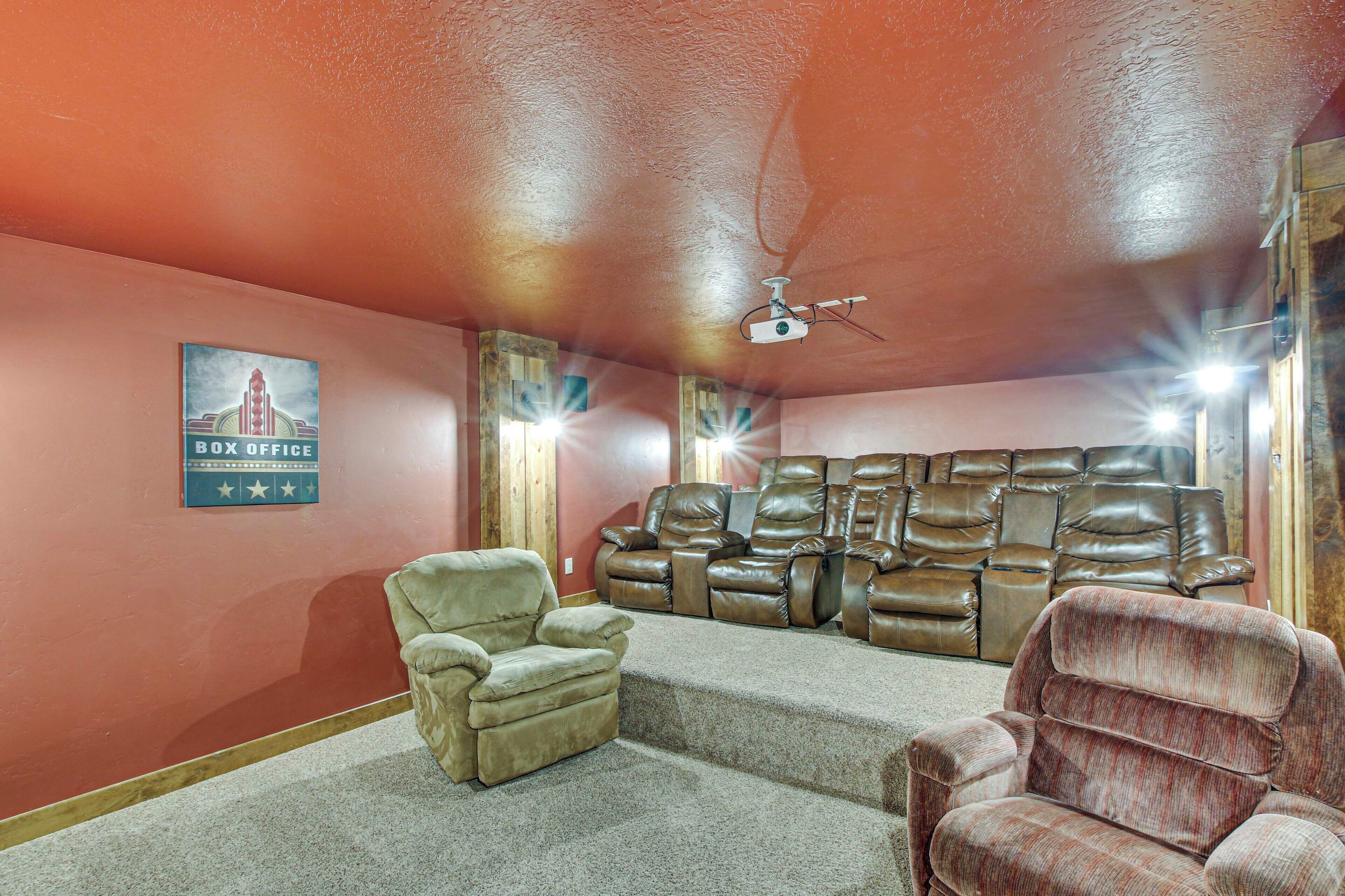 Une salle de cinéma maison équipée d’un grand canapé en cuir, d’un fauteuil inclinable et d’un projecteur fixé au plafond.