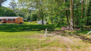 A rustic cabin with a small shed, surrounded by dense trees and a grassy yard. - Pet-friendly Raleigh Tiny Home w/ Patio (Raleigh)