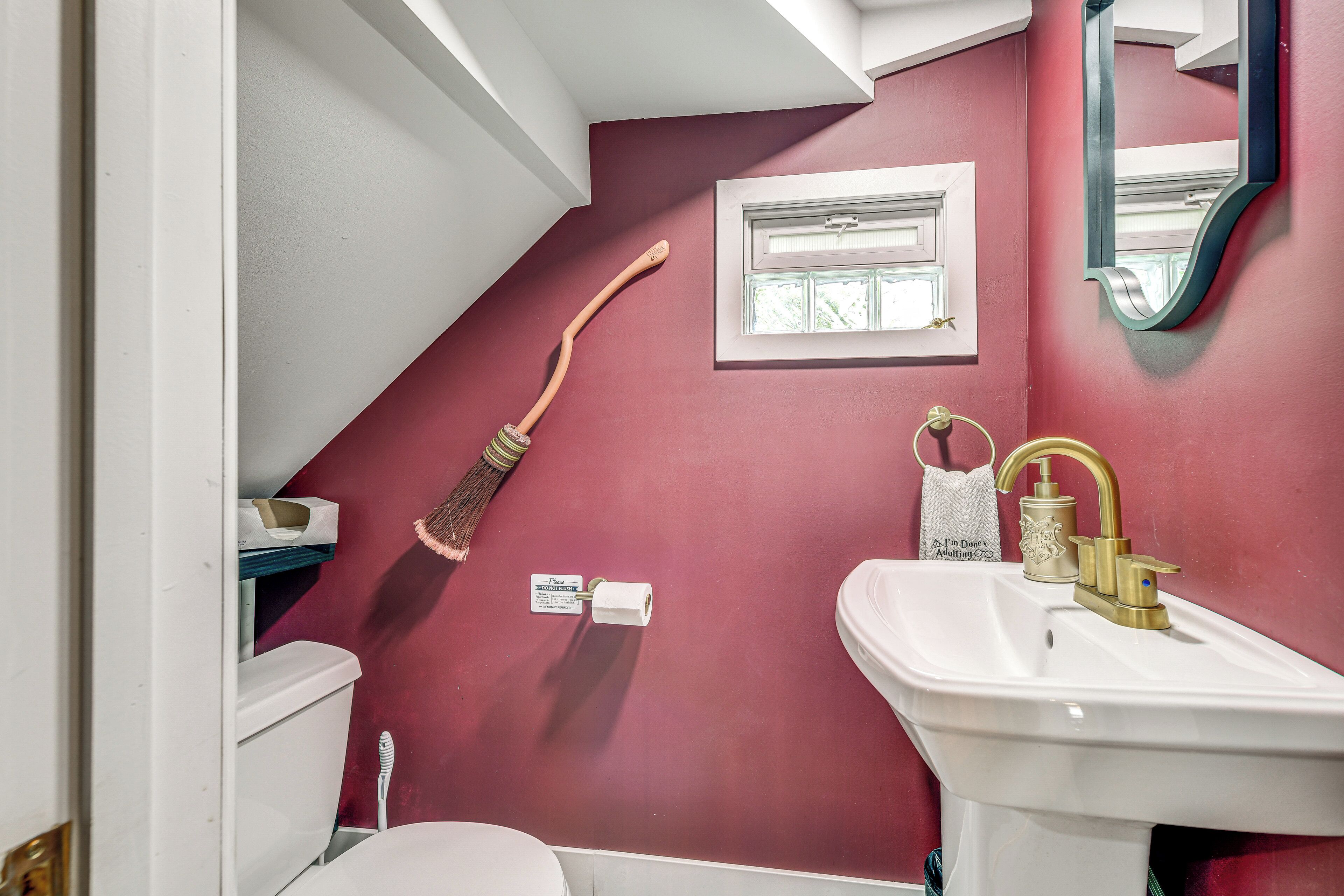 Ein Badezimmer mit einem weißen Waschbecken, einem Spiegel und einer roten Wand.