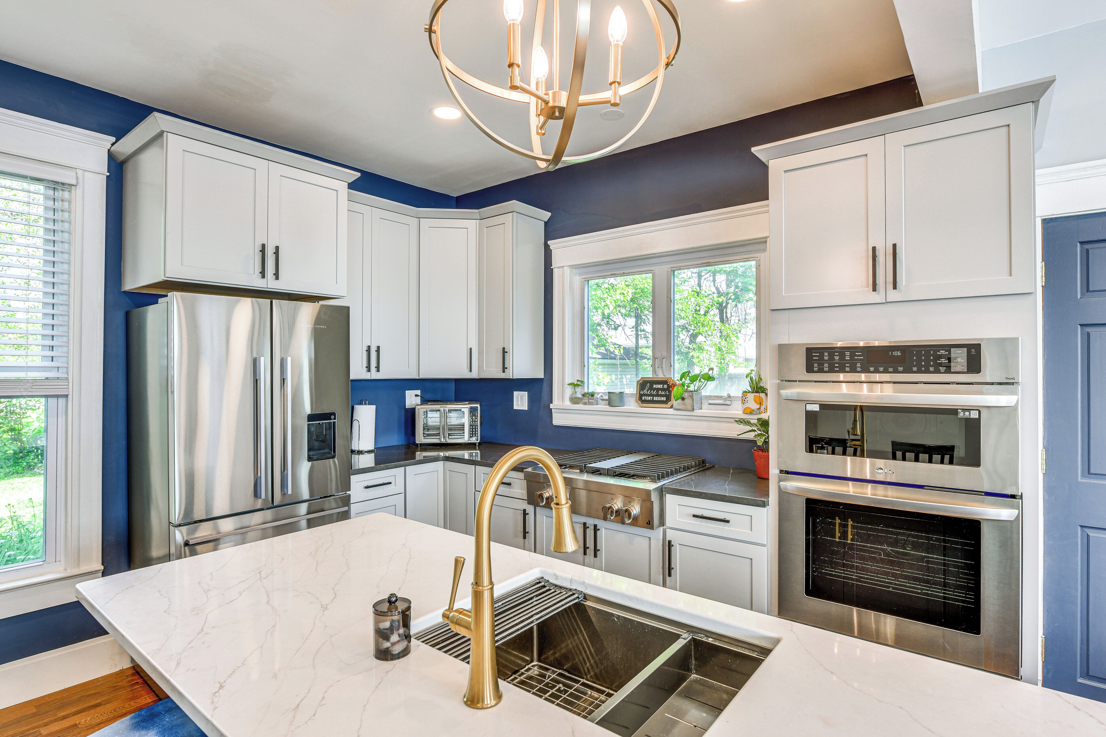 A modern kitchen with white cabinets, stainless steel appliances, and a marble countertop.
