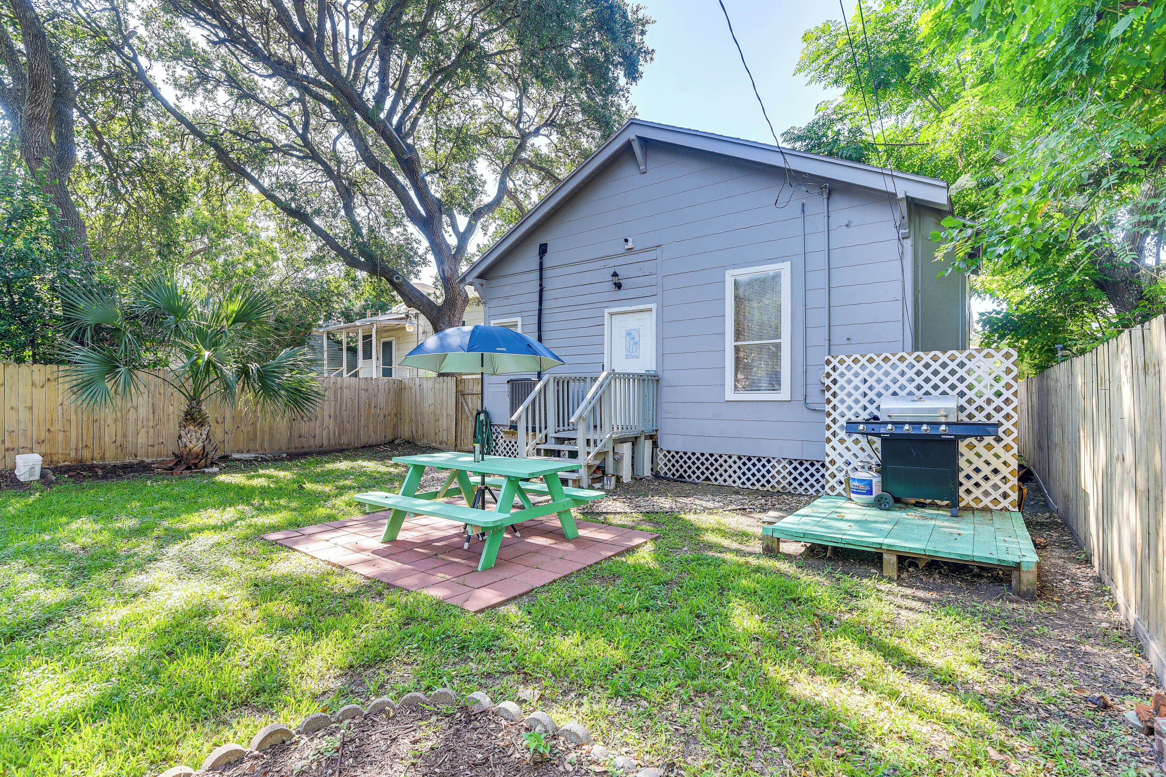 A backyard with a wooden deck, a picnic table, and a barbecue area.
