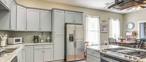 Une cuisine moderne avec des meubles gris, des appareils électroménagers en acier inoxydable et un plancher en bois.
