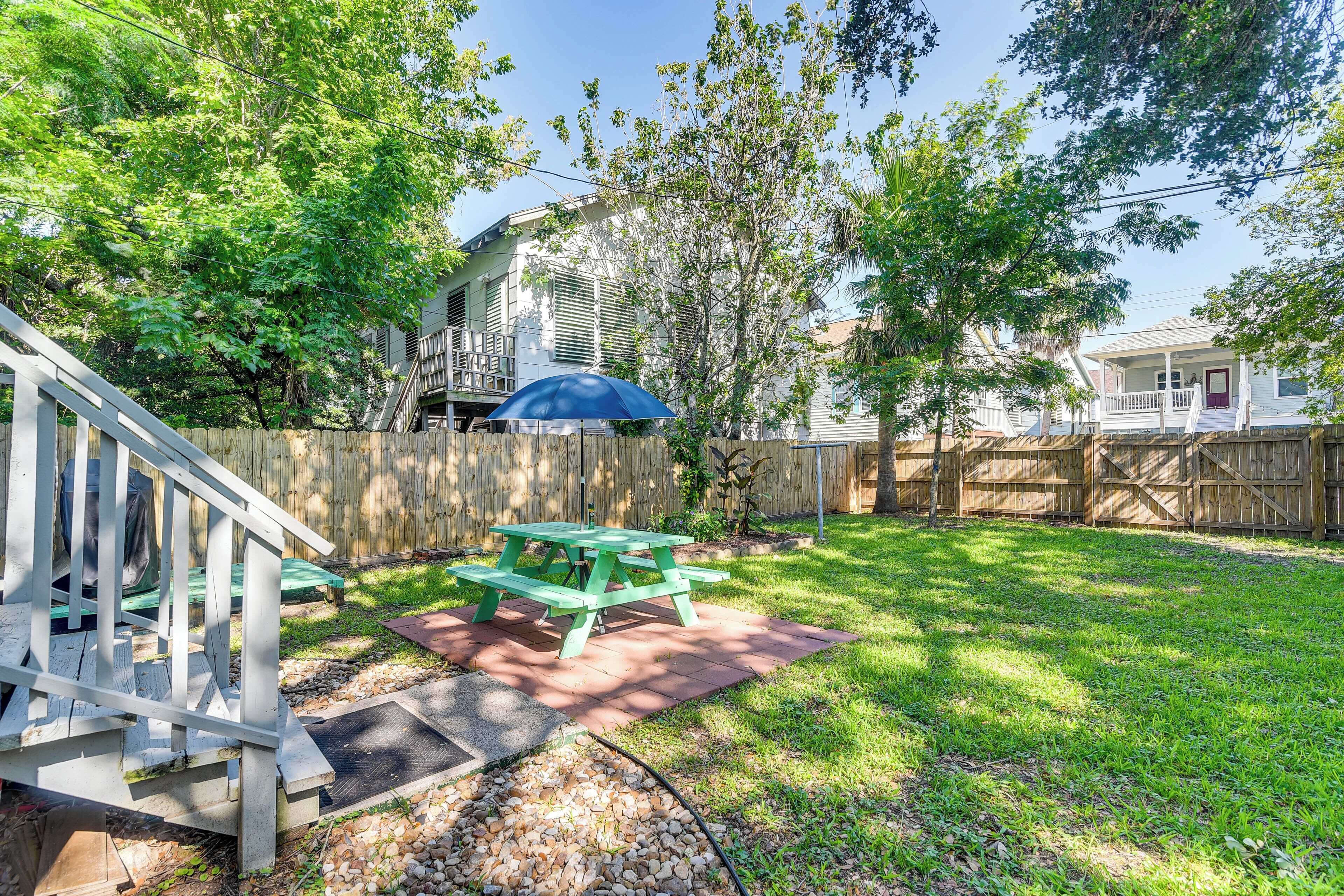 A backyard with a picnic table, a wooden deck, and a house in the background.