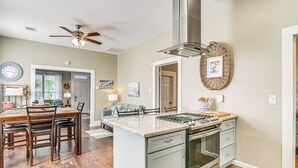 A kitchen with a central island, stove, oven, and a ceiling fan.