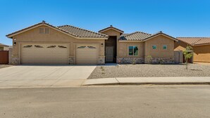 A two-story house with a garage, a small front yard, and a clear blue sky. - Year-round Yuma Escape Near Dtwn: Pets Welcome! (Yuma)