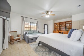 Ein Schlafzimmer mit einem Bett, einem Schaukelstuhl, einem Schreibtisch und einem Bücherregal.