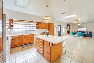 Una cocina amplia con armarios de madera, una isla grande y un comedor con sillas color turquesa.