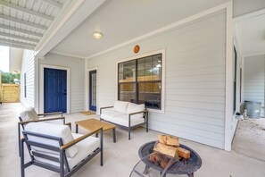 Eine überdachte Veranda mit einer blauen Tür, weißen Wänden und einer Sitzecke mit Tisch und Stühlen.