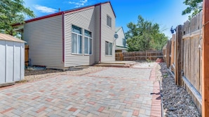 A backyard with a paved patio, a wooden fence, and a small shed. - 15 Mi to Downtown Denver: Home w/ Yard + Patio (Aurora)