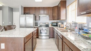 A modern kitchen with wooden cabinets, stainless steel appliances, granite countertops, and a built-in island. - 15 Mi to Downtown Denver: Home w/ Yard + Patio (Aurora)