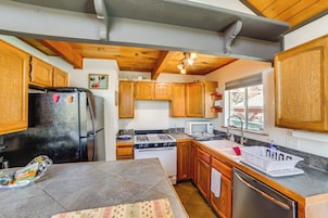 Una cocina compacta con armarios de madera, un refrigerador, estufa, microondas y lavavajillas.
