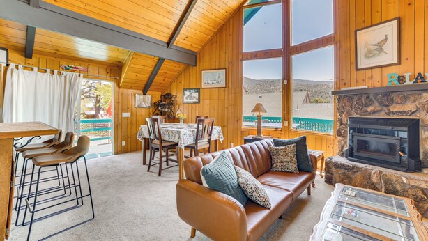 A cozy cabin interior with a wooden ceiling, a stone fireplace, a leather sofa, and a dining area with a table and chairs. - Frazier Park Cabin w/ Ping-pong Table, Near Trails (Frazier Park)