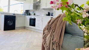 Una cocina moderna con armarios blancos, horno empotrado y lavadora.