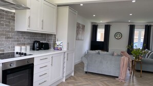 Una cocina moderna con armarios blancos, horno integrado y suelo de madera en espiga.
