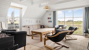 Een ruime loft met een hoge plafond, grote ramen met uitzicht op de omgeving, een houten eettafel en modern meubilair.