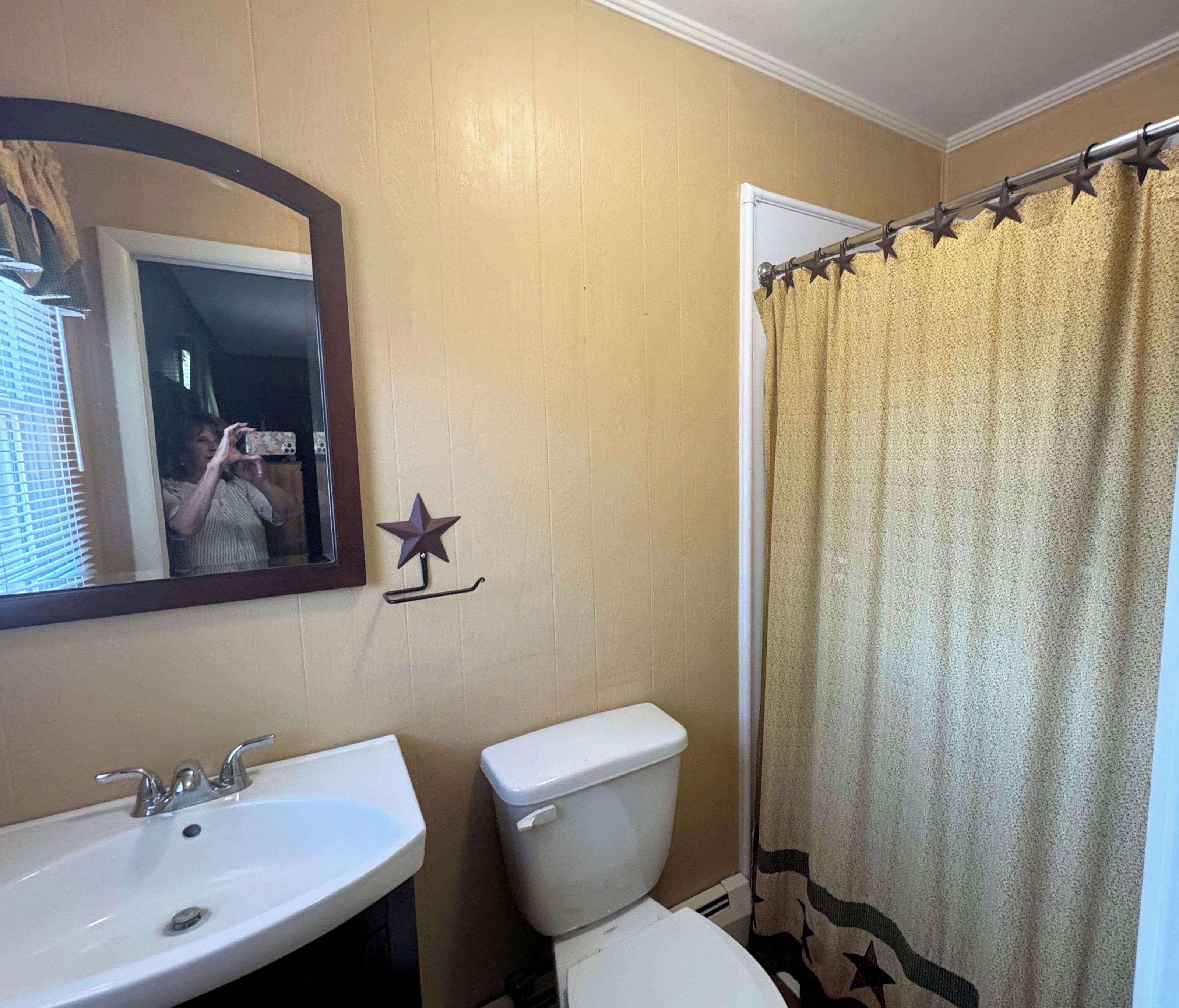 Une salle de bain avec un lavabo blanc, des toilettes et un rideau de douche orné de motifs en forme d’étoiles.