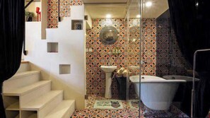 Bathroom features a pedestal sink, bathtub, and a unique tile design.