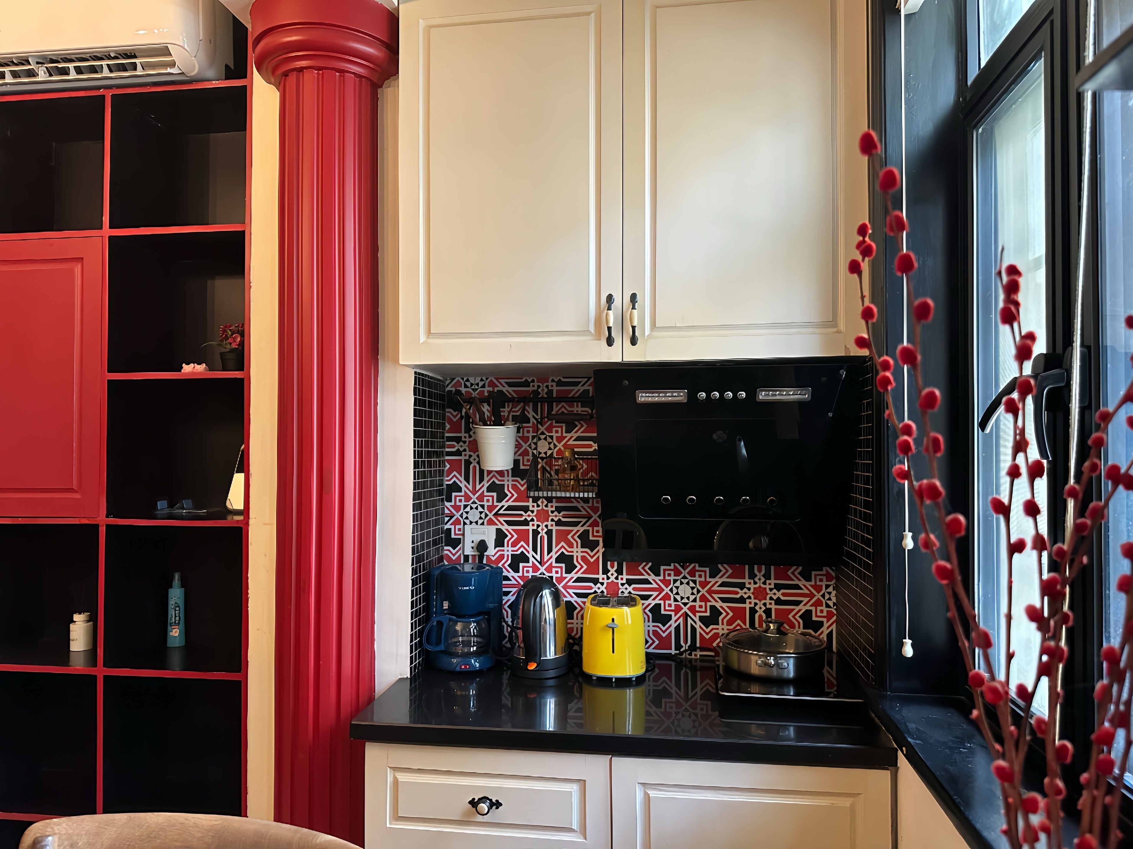 A kitchen with white cabinets, a black countertop, and red accents.