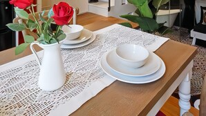 A dining area with a wooden table, white pitcher, red roses, and a chandelier. - Lian's Cozy Cottage next to ShaanXi S. Rd Subway STA nestled in Mid. Huaihai Rd. (Shanghai)