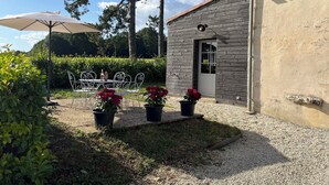 Eine Terrasse mit Tisch und Stühlen, umgeben von Kübelpflanzen und einer Pergola.