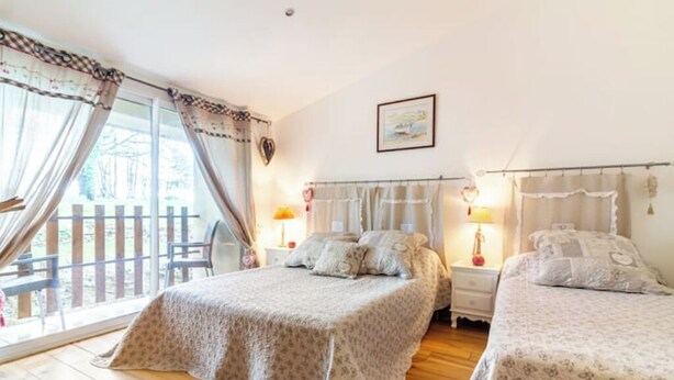 A bedroom with two beds, a wooden floor, a balcony with a wooden fence, and a wall-mounted picture.