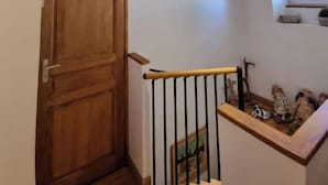 A wooden door with a nameplate, a staircase with a metal railing, and a small window with a shelf above it.