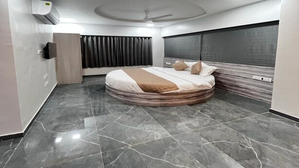 Une chambre moderne avec un lit aux lignes courbes, un ventilateur de plafond et une grande fenêtre agrémentée de rideaux.