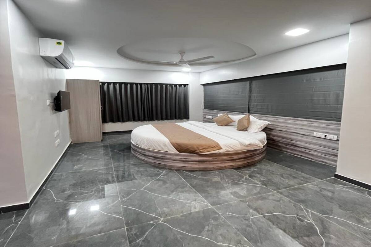 Un dormitorio moderno con una cama curvada, un ventilador de techo y un ventanal con cortinas.