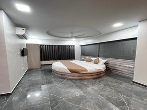 Ein modernes Schlafzimmer mit einem gebogenen Bett, einem Deckenventilator und einem großen Fenster mit Vorhängen.