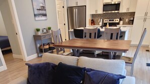 A modern living room with a beige sofa, a wooden coffee table, and a kitchen in the background.
