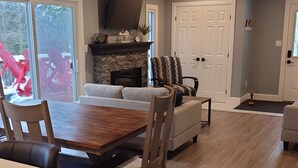 A spacious living area with a wooden dining table, a sofa, and a fireplace.