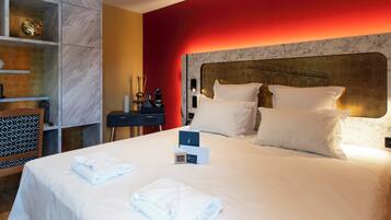 Habitación de hotel con una cama grande, ropa de cama blanca, cabecera de mármol y una pared de acento roja.