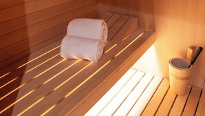 Una sauna con bancos de madera, una toalla y un cubo.