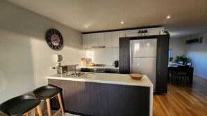 A modern kitchen with a central island, stainless steel appliances, and a dining area with a table and chairs.