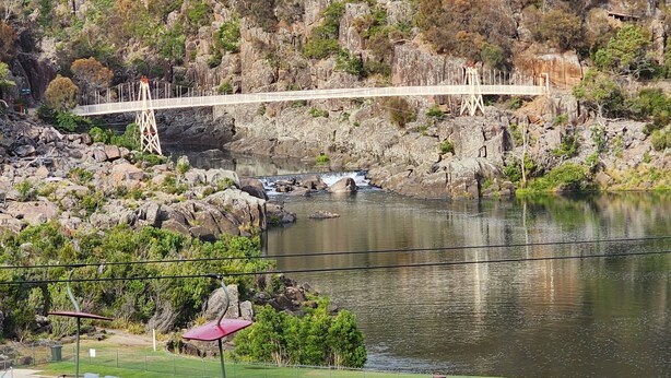 A swimming pool with a view of a rocky hillside and a bridge.