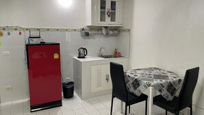 A compact kitchen with a red refrigerator, a sink, and a table with chairs. - Impact Muangthong C1-C9 by Anna (Pak Kret)