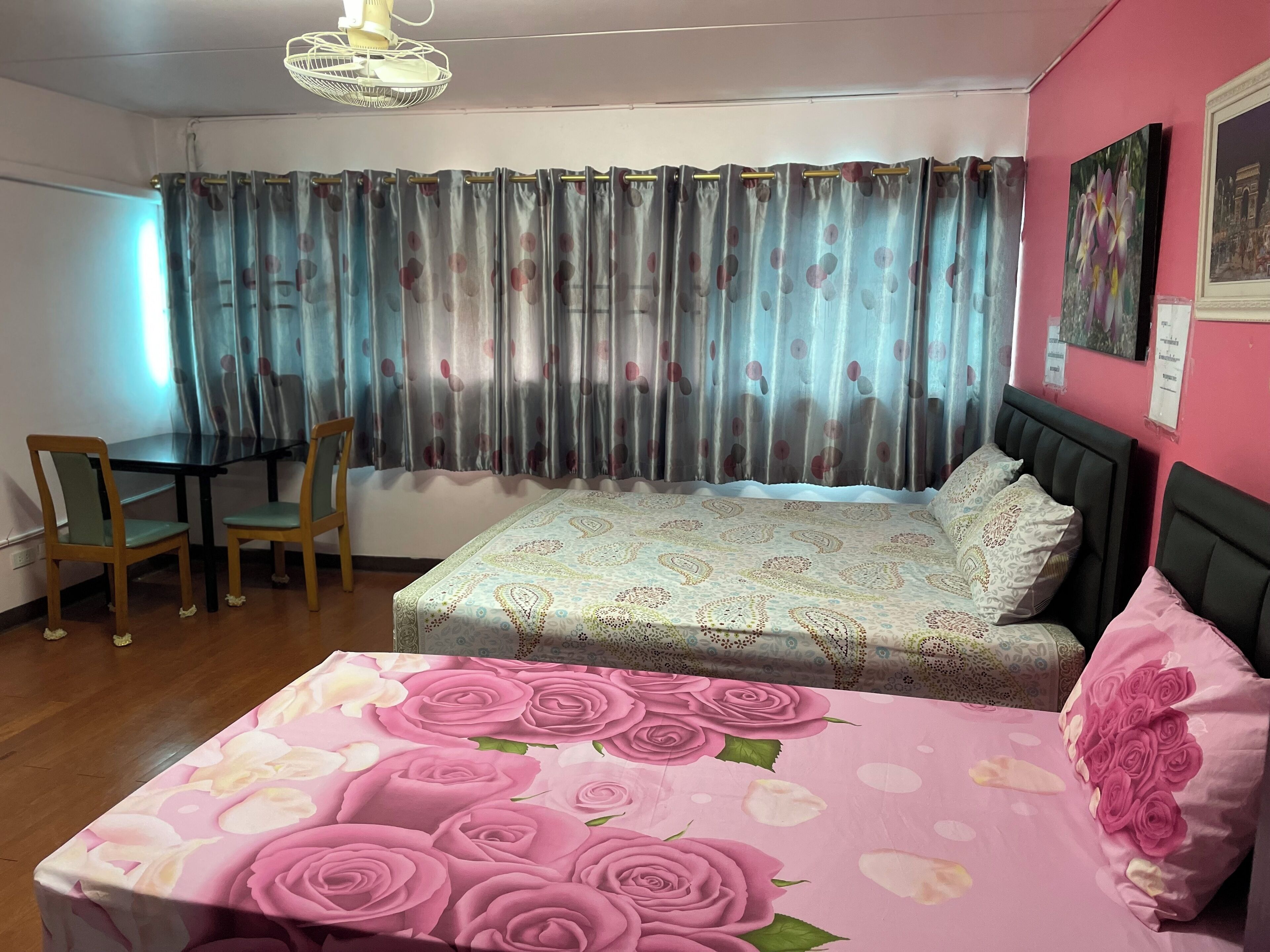 A bedroom with a bed, a chair, a table, and a window with curtains.