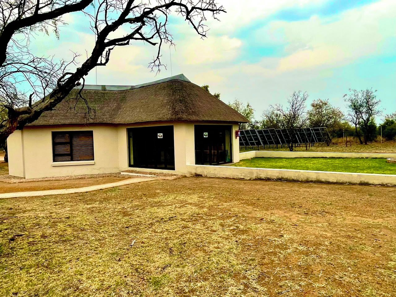 A building with a thatched roof, two garage doors, and a grassy lawn.