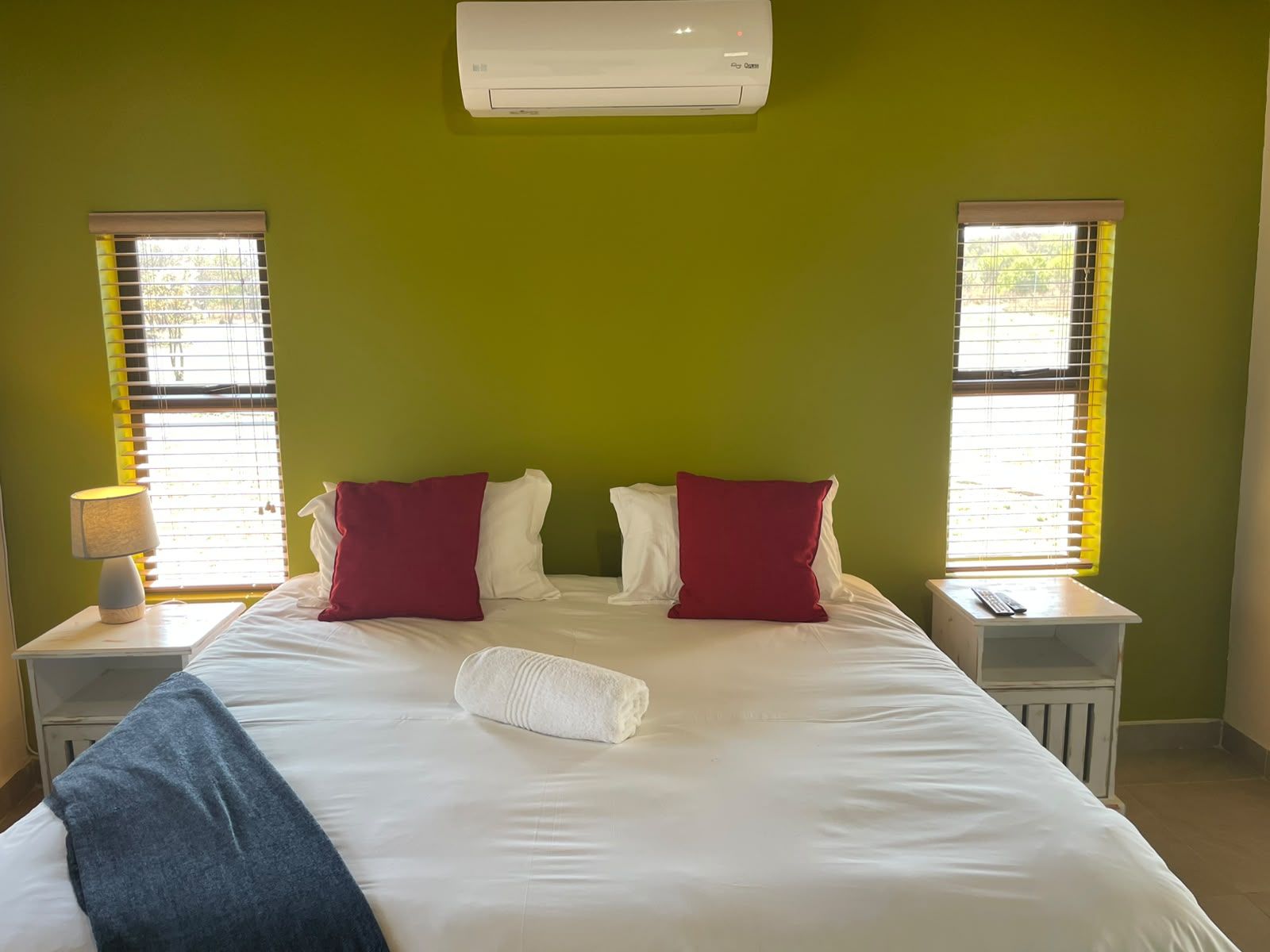 Een hotelkamer met een bed, twee nachtkastjes, een lamp en een airconditioner.