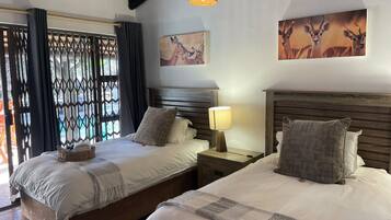 A hotel room with two beds, a nightstand with a lamp, and artwork on the walls.