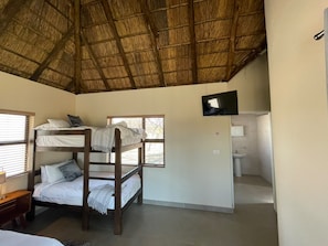 A room with bunk beds, a television, and a bathroom. - Halali Wilderness Game Ranch (Hammanskraal)