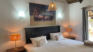 A bedroom with a large bed, two bedside lamps, a wall-mounted picture, and a ceiling fan.