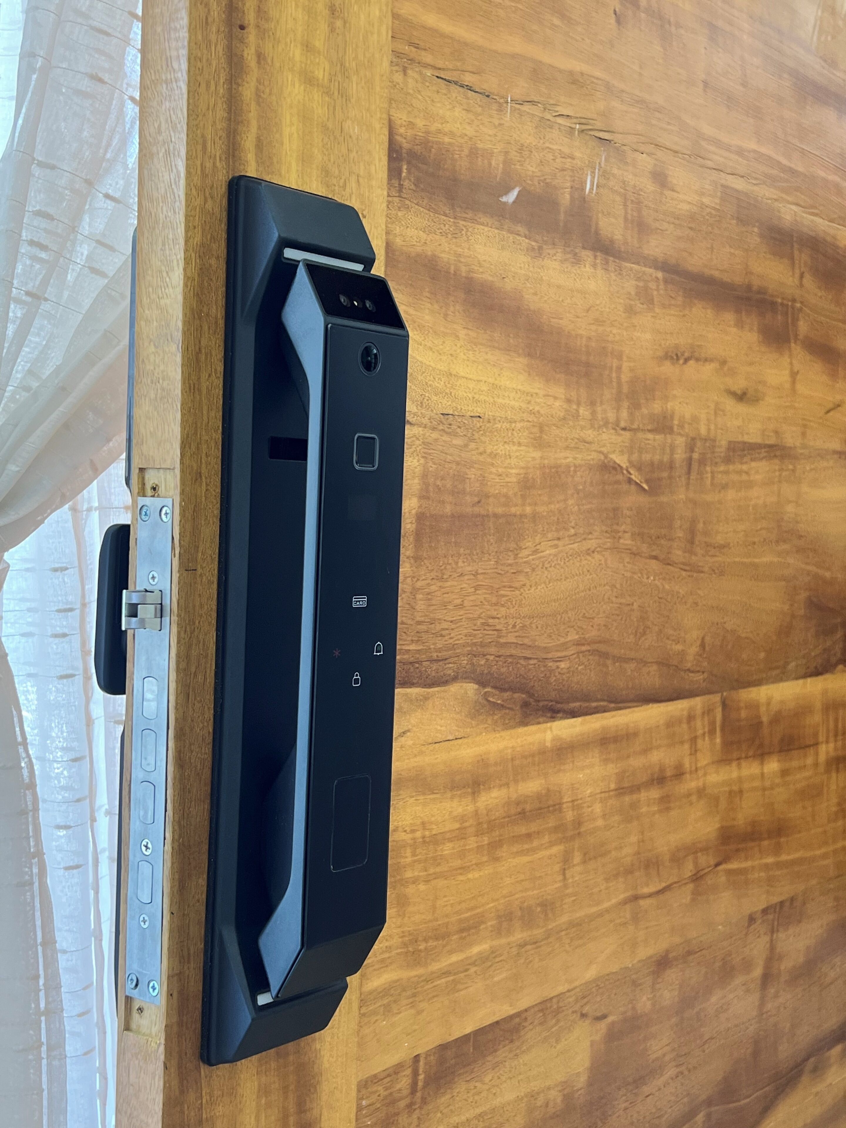 Um objeto preto fixado em uma superfície de madeira, possivelmente um aparelho ou equipamento.