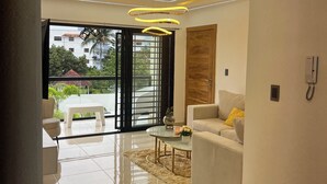 A modern living room with a sofa, coffee table, and a glass door leading to a balcony. - Ático de lujos  (Santiago de los Caballeros)