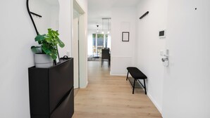 A modern hallway with a potted plant, a bench, and a mirror on the wall. - Stil und Komfort Terrasse - Parkplatz (Bielefeld)
