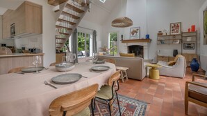 Une salle à manger spacieuse avec un plafond haut, des poutres en bois et une grande table dressée pour le repas.