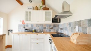Una cocina moderna con armarios blancos, encimera de madera, horno empotrado y microondas.