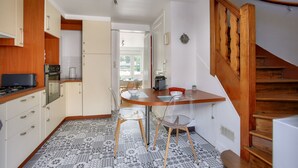 A kitchen with wooden cabinets, a dining table with chairs, and a staircase.
