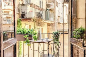 Un balcón con una mesa, sillas y plantas en macetas.
